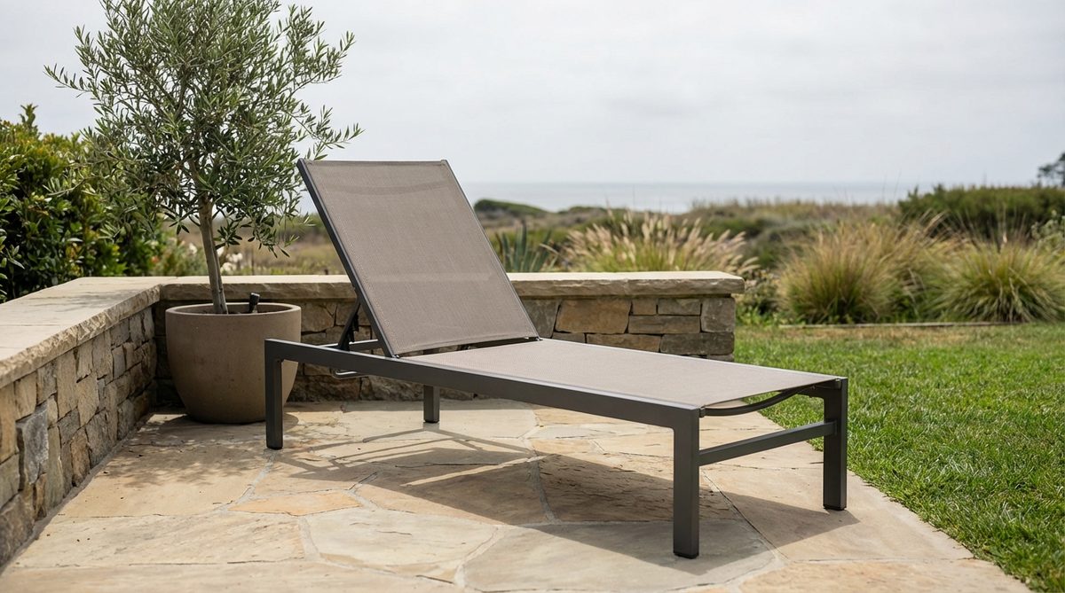 A minimalist aluminum sling lounger with breathable textile stretched across a durable frame, perfect for small patios or balconies. The lounger features earth-toned sling material that drains quickly after rain and provides ergonomic support, with corrosion-resistant aluminum construction for long-lasting use in coastal environments.