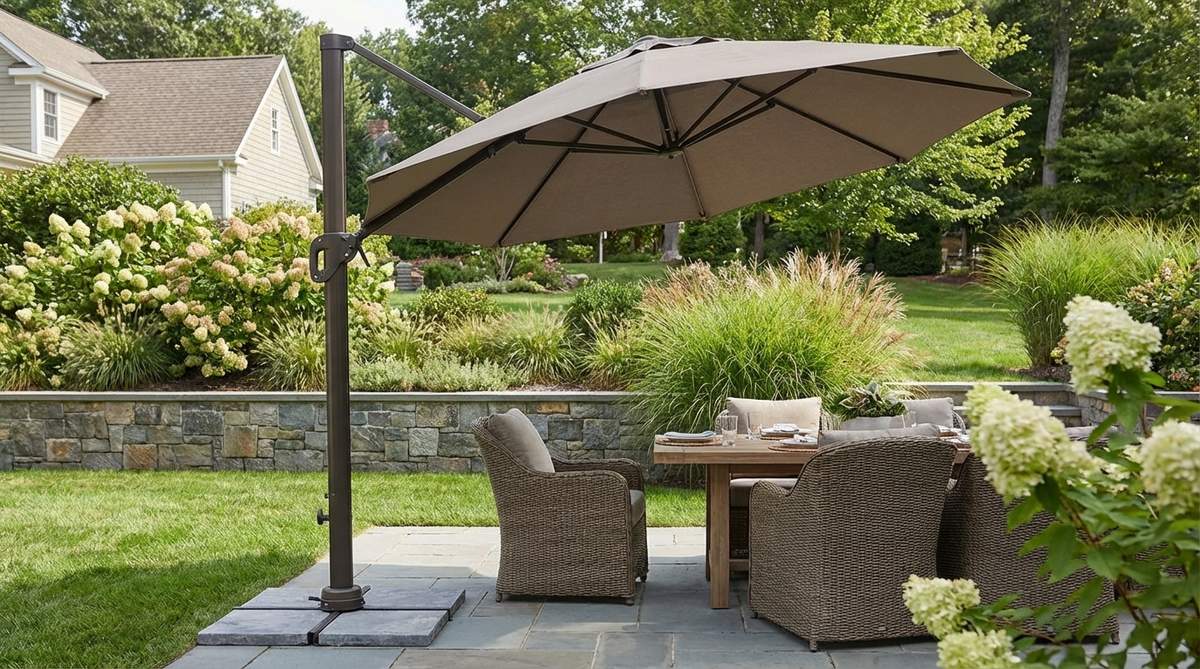 A modern cantilever offset umbrella with a side-mount pole that eliminates center obstruction, ideal for dining or seating areas. Features a crank mechanism for adjusting the canopy angle to follow the sun, solution-dyed fabric for fade resistance, a weighted base for stability, 350-degree rotation for comprehensive shade coverage, and neutral colors for a calming atmosphere in garden settings.